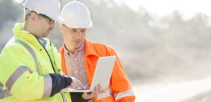 Construction workers using a laptop on site