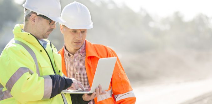 Construction workers using a laptop on site