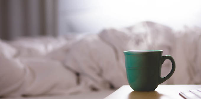 Coffee cup next to a bed doona days sick leave