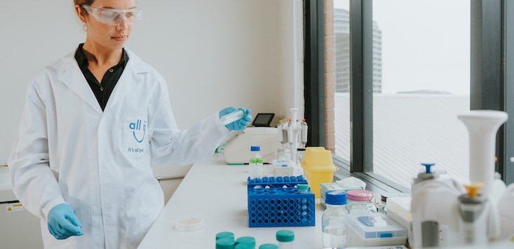 All G Foods laboratory interior shot, woman in labcoat holds apparatus