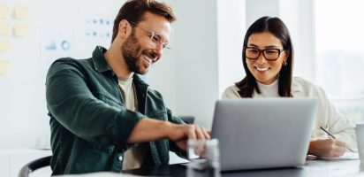 Two business people using a laptop together in an office