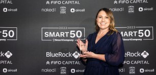 Melissa Pain posing with Smart50 Award in front of media wall