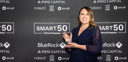 Melissa Pain posing with Smart50 Award in front of media wall